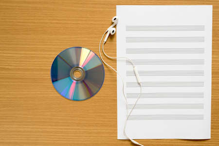 top view of music staff paper dvd dish and earphone on wood backgroundの写真素材