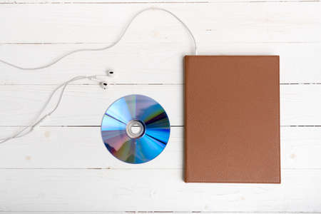 top view of book dcd disc and earphone on white wood backgroundの写真素材