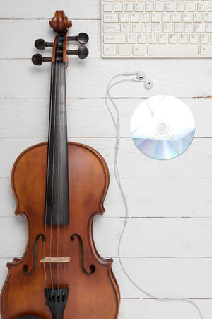 keyboard computer with dvd disc and violin on white wood backgroundの写真素材
