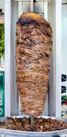 Delicious slabs of skewered fast food shawerma chicken and lamb meat turn side by side on a spit. This is part of a common sandwich found in the Middle East.の写真素材