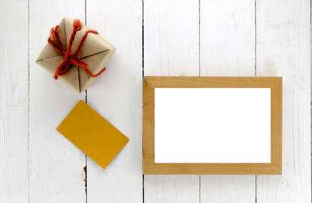 top view of gift box with card and photo frame on white wood background