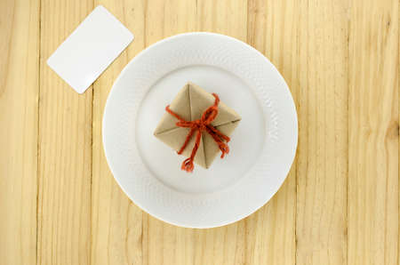top view of craft gift box on dish on wood background concept food for giftの写真素材
