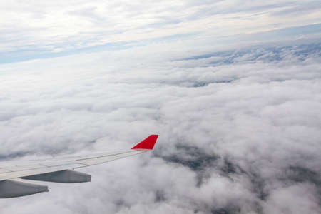 Wing of an airplane flying above the clouds の写真素材