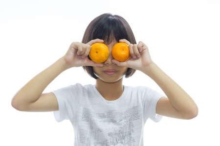 Beautiful girl holding oranges to her eyes on white background.の写真素材