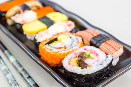 Japanese sushi traditional food on black plate with chopsticks isolate background. の写真素材
