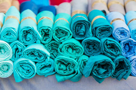 Row of variety multicolored shirt clothes hanging on shelf outdoor for sale, no brandnames or copyright objects. の写真素材