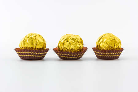 Sweet chocolate ball wrapped in golden foil isolated on white background.の写真素材