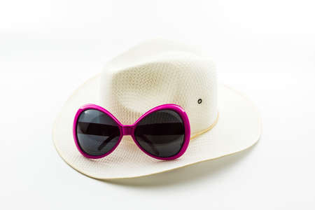 White woven hat with pink sunglasses on white background. の写真素材