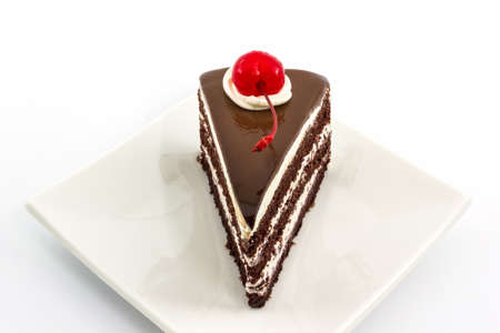 Chocolate cake slice with red cherry fruit on white plate. の写真素材