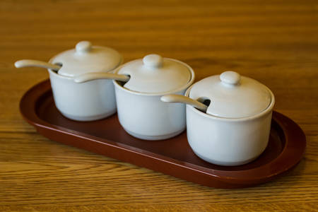 White ceramic kitchen spice jars in a row on wood.