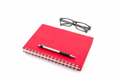 Red Diary Book with old glasses and pen on white background.の写真素材