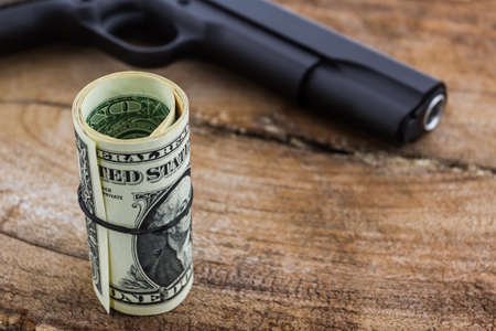 Close up money with Gun on wood background.の写真素材