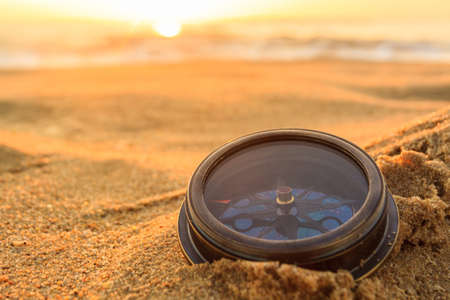 Ancient compass on the sand at the Beach Sunrise ,nature background .の写真素材