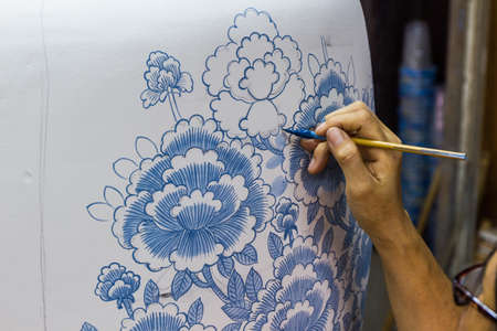 Hand with paintbrush painting a jar, handicraft.の写真素材