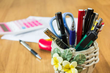 Office supplies including a pen, scissors, cutter in beautiful box on wood table.