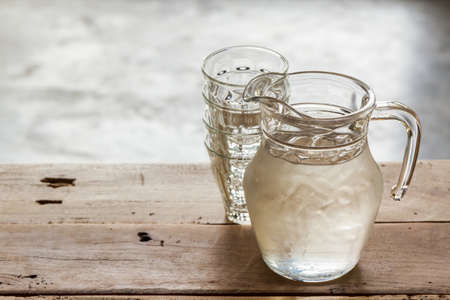 Glass pitcher of water and glass on wooden table background.の写真素材