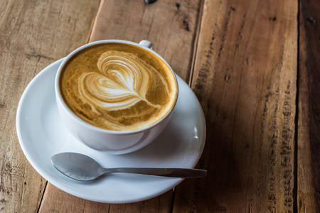 Cappuccino or latte coffee on wooden table in the cafe.