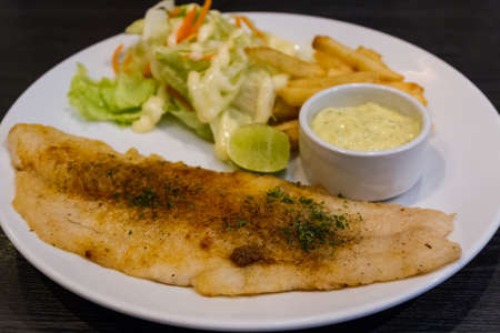 Fish steaks and vegetable salad with french fried on white plates.の写真素材