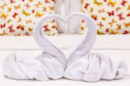Two swans heart shaped made from towels on honeymoon bed.の写真素材