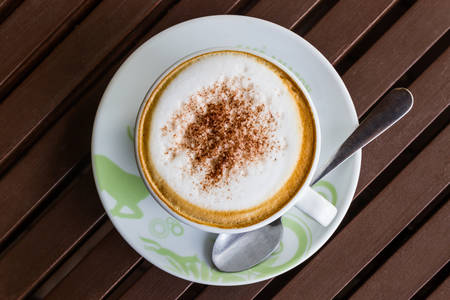 Cappuccino or latte coffee on wooden table in the cafe.