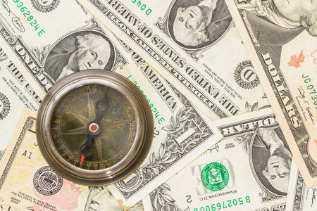 Closeup of compass on a heap of paper dollars.の写真素材