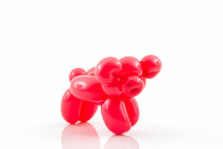 Balloon animal of red pig action pose on white background.の写真素材