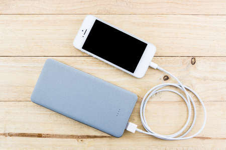 Smartphone with grey powerbank on wood desk.の写真素材