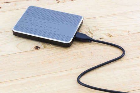 External hard drive for backup on wood background.の写真素材
