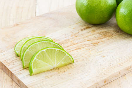 Limes slices on wooden cutting board.の写真素材