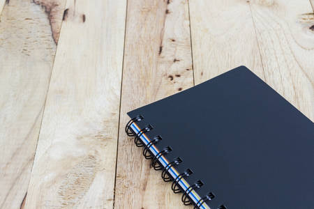 Black spiral notebook on wood background.の写真素材