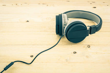 Black Headphones on wood desk Background. Vintage color tone.の写真素材