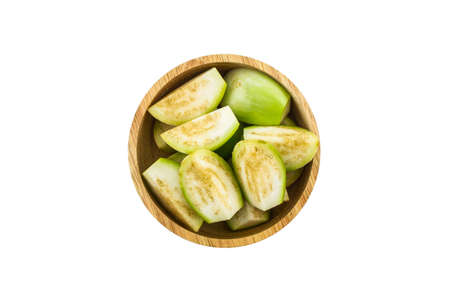 Thai green eggplant slices in the wood bowl on white background.の写真素材