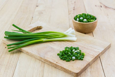 Chopped spring onions on wooden cutting board.の写真素材