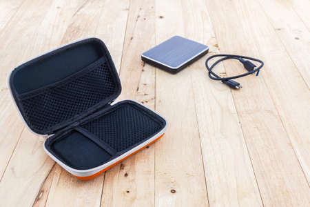 External hard drive carrying case. Bags for external hard drive on wood background.の写真素材