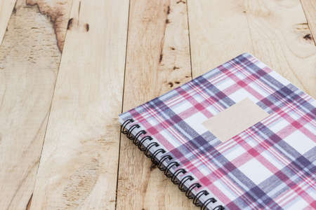 Fabric plaid texture cover spiral notebook on wood background.の写真素材