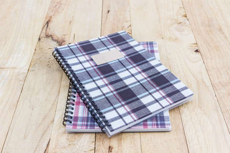Fabric plaid texture cover spiral notebook on wood background.