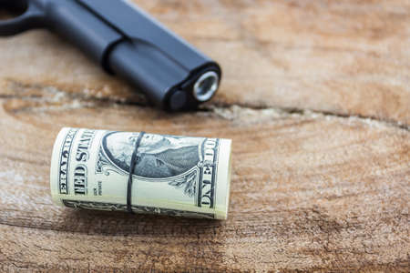 Close up money with gun on wood background.