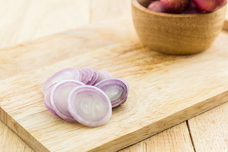 Red onion slices on wooden cutting board.の写真素材