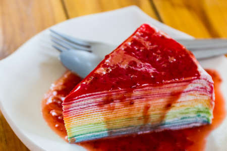 Rainbow crepe cake with strawberry sauce.