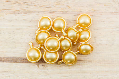 Hair vitamin serum capsule gold color on wood background.の写真素材