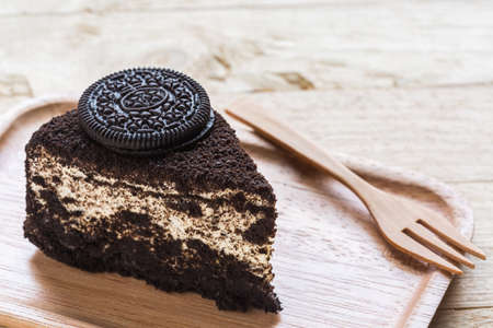 Chocolate cake slice in wooden plate on the wooden table.の写真素材