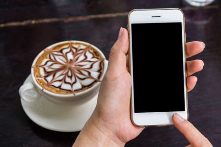Close up of a woman using mobile smart phone in coffee shop.の写真素材