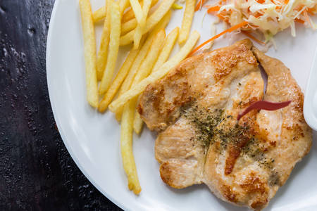 Grill chicken steak and French Fries (potato chips), vegetable salad on a white plate.の写真素材