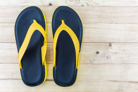 Colorful of Sandals shoes / Orange and black colors flip flops on wood background.の写真素材