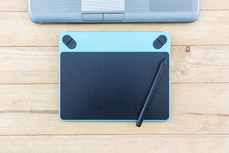 Digital graphic tablet and pen isolated on wood desk Background.の写真素材