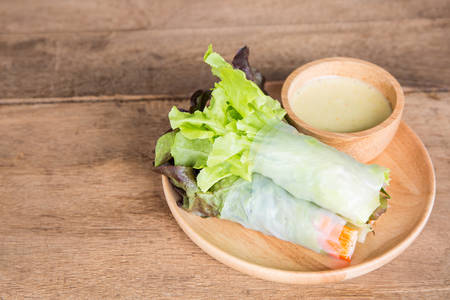Vegetable salad in wooden plate on the wooden table.の写真素材
