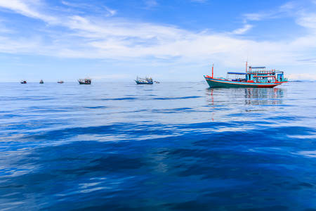 Fishing boat floating in the sea. The beautiful bright blue sky and blue water in a clear day.の写真素材