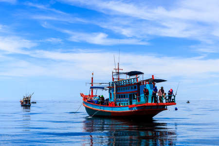 Fishing boat floating in the sea. The beautiful bright blue sky and blue water in a clear day.の写真素材