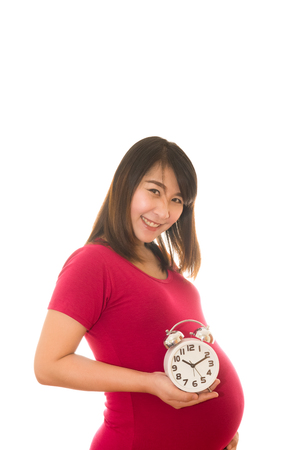 Pregnant woman holding wall clock. It's time. Isolated on white.の写真素材