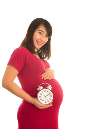 Pregnant woman holding wall clock. It's time. Isolated on white.の写真素材